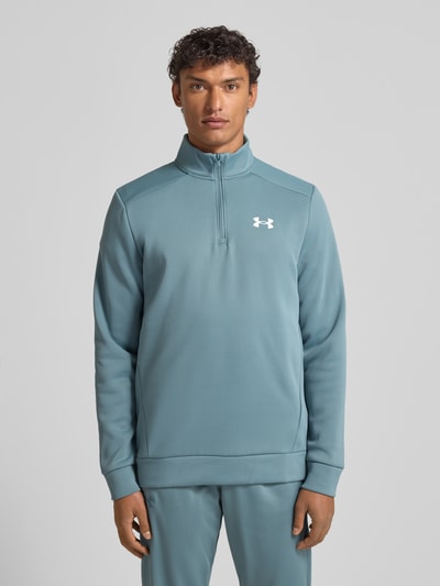 Männermodel trägt Sweatshirt mit Label-Detail von Under Armour in Blau mit Stehkragen, kurzem Reißverschluss, Lockerer-Schnitt, Gerippte-Abschlüsse, Rückenlänge 72 cm, Ärmellänge 67 cm, Ganzkörperansicht von vorne.