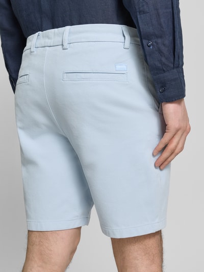 Männermodel trägt Modern Fit Chinoshorts aus Baumwoll-Mix Modell 'KANE1' von BOSS, unifarben, Rückansicht, Nahaufnahme Hüfte.