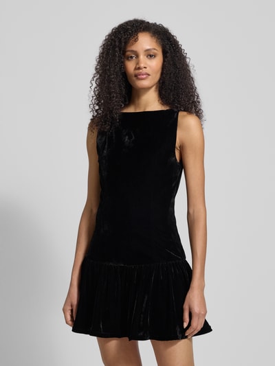 Frauenmodel trägt Minikleid mit U-Boot-Ausschnitt von Mango aus schwarzem Material-Mix mit Stretch-Anteil, taillierter Schnitt, ausgestellte Rockpartie, Rückenlänge bei Größe M 83 cm, Brustweite 41 cm, Nahaufnahme Oberkörper.