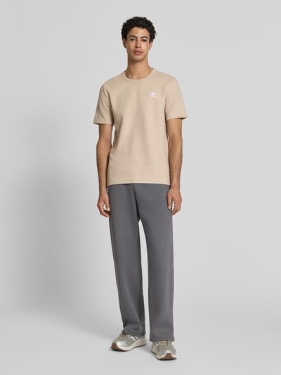 Męski model nosi Regular Fit T-Shirt mit Baumwoll-Anteil von adidas Originals, efekt: jednolity kolor, krój regular fit, wzór: faktura wafla, okrągły dekolt, wyhaftowane logo, rękaw: krótki rękaw, Ganzkörperansicht von vorne.
