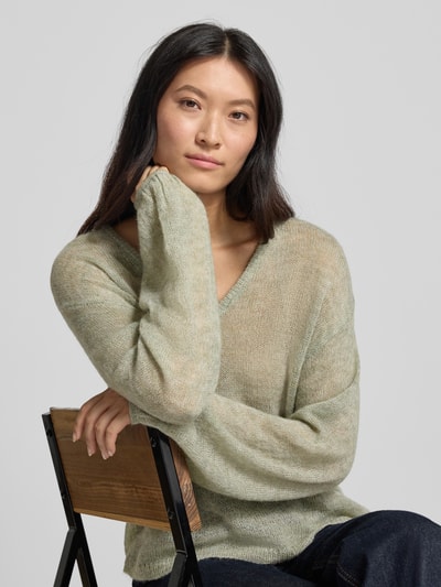Vrouwenmodel draagt Relaxed Fit pullover met alpaca-aandeel Model 'Dido' van FREE/QUENT, mix van katoen en alpacawol, semi-transparant, V-hals, groene tinten, zachte stofstructuur, ruglengte maat S 56 cm, mouwlengte 55 cm, Nahaufnahme Oberkörper.