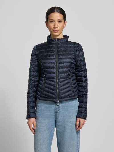 Frauenmodel trägt Steppjacke mit Stehkragen von Gil Bret in Dunkelblau, Zweiwege-Reißverschluss, Reißverschlusstaschen, körpernahe Passform, Rückenlänge 56 cm, Schulterbreite 39 cm, Brustweite 47 cm, Ärmellänge 66 cm, Ganzkörperansicht von vorne.
