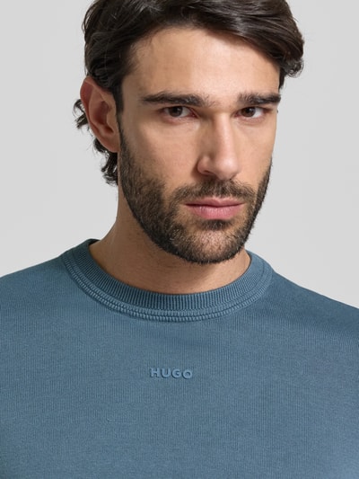 Männermodel trägt Regular Fit Strickpullover aus reine Baumwolle Modell 'SAN CASSIUS-C2' von HUGO in Blau, Nahaufnahme Oberkörper.