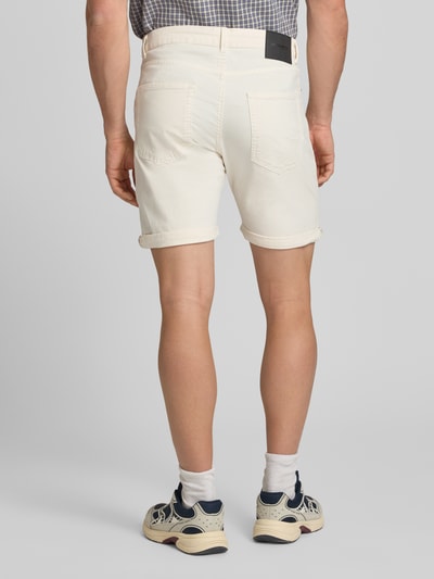 Männermodel trägt Jeansshorts mit Umschlag und Eingrifftaschen Modell 'RICK ALLEN' von Jack & Jones aus Baumwoll-Elasthan-Mix, Regular-Fit, Farbe Creme, strukturierte Oberfläche, Bundweite Größe M 43 cm, Innenbeinlänge 20 cm, Ganzkörperansicht Rückansicht.