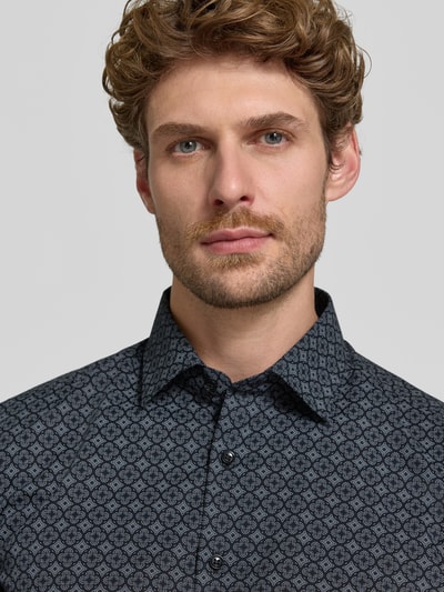 Männermodel trägt Body Fit Businesshemd aus reiner Baumwolle von OLYMP Level 5, feines schwarzes Muster, Nahaufnahme Oberkörper.