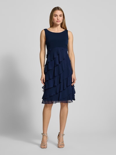 Kobiece model prezentuje knielanges Cocktailkleid mit Volants von Swing z szyfonu, linia A, długość do kolan, okrągły dekolt, ciemnoniebieska, szerokość klatki piersiowej 31 cm, długość tyłu 103 cm, rozmiar 36, Ganzkörperansicht von vorne.
