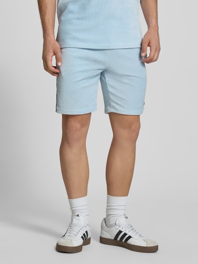 Mężczyzna nosi Shorts aus Cord Modell 'TOMATRO' od Ellesse, bawełniany miks z dodatkiem stretchu, krój regular fit, kolor jasnoniebieski, elastyczny pas z tunelem, szerokość w rozmiarze M: 42 cm, długość wewnętrzna nogawki: 21 cm, widok całej sylwetki z przodu.