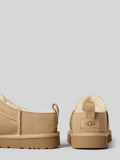 Produktfoto, Hausschuhe mit Label-Detail von UGG aus beschichtetem Leder-Mix in Beige, abgerundete Spitze, strukturierte Sohle, Absatzhöhe 3 cm, Schafthöhe 4 cm, Schaftweite 7 cm, Label-Detail auf der Ferse.