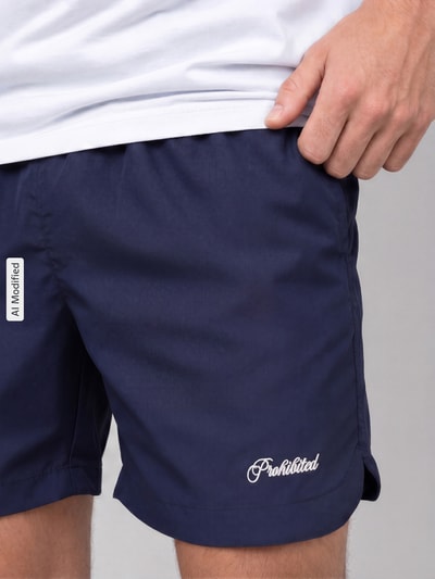 Männermodel trägt Badehose mit Label-Stitching und elastischem Bund von PROHIBITED, dunkelblau, Regular Fit, Nahaufnahme Oberschenkel.