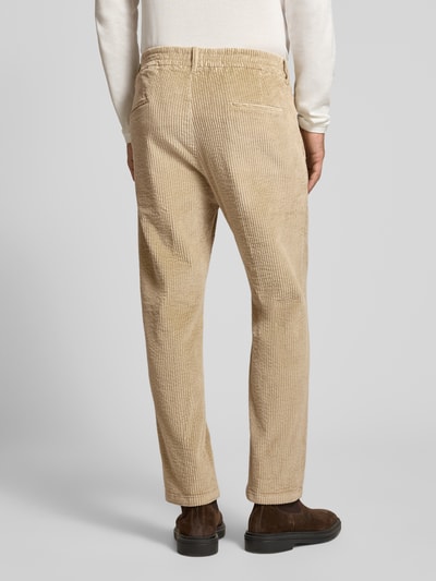 Männermodel trägt Straight Fit Hose aus Baumwoll-Mix Modell 'Chasy' von DRYKORN in Beige mit Cord-Optik, Gesäßtaschen, Ganzkörperansicht Rückansicht.