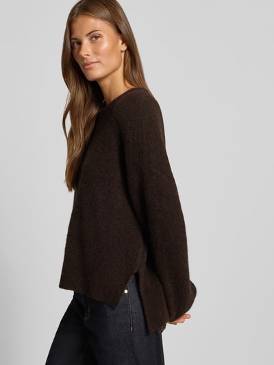 Frauenmodel trägt dunkelbraunen Relaxed Fit Pullover aus Woll-Alpaka-Mix Modell 'Alpha' von Gestuz in Strick-Optik, Seitenansicht, Nahaufnahme Oberkörper. Rückenlänge 52 cm, Ärmellänge 49 cm.