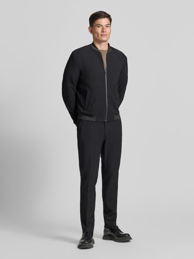 Männermodel trägt schwarzen Blouson mit seitlichen Eingrifftaschen von MCNEAL, elastische Abschlüsse, Regular Fit, Ganzkörperansicht von vorne.