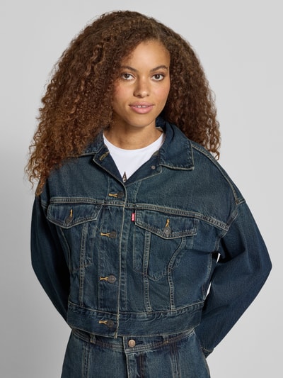 Frauenmodel trägt Jeansjacke mit Label-Detail Modell 'LOOSE CROP TRUCKER' von Levi's® 300, dunkles Denim, strukturierte Oberfläche, Nahaufnahme Oberkörper.