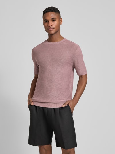 Męski model nosi Slim Fit T-Shirt aus Leinen-Mix in Strick-Optik von Antony Morato, mieszanka lnu i wiskozy, krój slim fit, imitacja dzianiny, okrągły dekolt, z krótkim rękawem, elastyczne wykończenia, długość tyłu w rozmiarze M: 72 cm, kolor jasnoróżowy, gładka tekstura, Ganzkörperansicht von vorne.