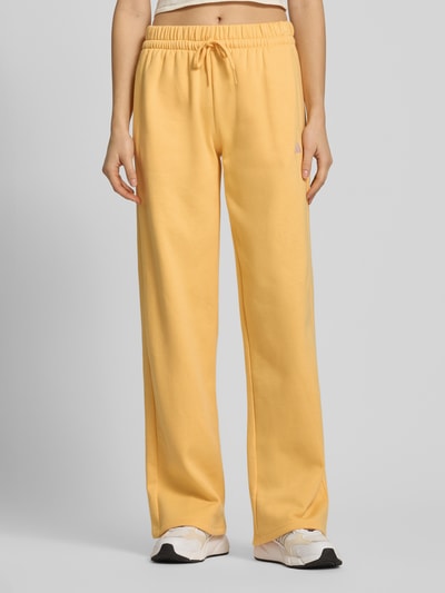 Kobiece model nosi Sweatpants mit Logo und elastischem Bund od adidas Sportswear, mieszanka bawełny, krój regular fit, logo, elastyczny pas, tunel, długość wewnętrzna nogawki 79 cm przy rozmiarze S, widok całego ciała z przodu.