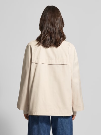 Modelka kobieca ma na sobie Relaxed Fit Jacke mit Stehkragen od comma z mieszanki bawełny, kolor jasny, widok całej sylwetki z tyłu. Długość tyłu w rozmiarze S: 70 cm, szerokość ramion w rozmiarze S: 48 cm, szerokość klatki piersiowej w rozmiarze S: 58 cm, długość rękawów w rozmiarze S: 73 cm, wpuszczane kieszenie, elastyczne zakończenia rękawów, pełna listwa guzikowa.