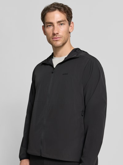 Männermodel trägt schwarze Regular Fit Trainingsjacke mit Label-Print Modell 'OW_Airynix JT HD 2' von BOSS Green, Nahaufnahme Oberkörper.