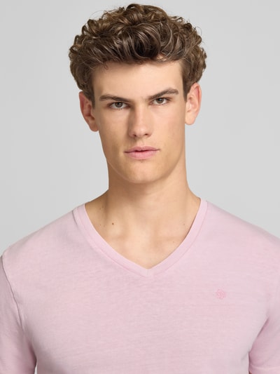 Männermodel trägt T-Shirt aus Baumwoll-Leinen-Mix mit V-Ausschnitt von Superdry, blassrosa, Stitching, Regular-Fit, Nahaufnahme Oberkörper. Rückenlänge bei Größe M: 68 cm.