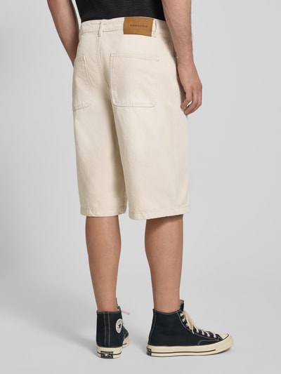 Männermodel trägt Straight Fit korte broek in denimlook model 'Kolar' van PEGADOR, puur katoen, 5-pocketmodel, knoop- en ritssluiting, bandwijdte maat 32: 43 cm, binnenbeenlengte maat 32: 33 cm, geheel in lichte beige tint, textuur lijkt op denim, detailopname van achteren.