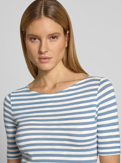 Frauenmodel trägt Slim Fit T-Shirt aus reiner Baumwolle von Marc O'Polo mit Optik:Allover-Muster, gestreift, Logo-Print, U-Boot-Ausschnitt, Kurzarm, in Blau-Weiß, Struktur fein und glatt, Nahaufnahme Oberkörper.