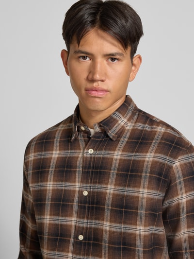 Männermodel trägt Regular Fit Freizeithemd mit Kentkragen Modell 'FIELD' von JACK & JONES, kariertes Muster in Braun und Beige, reine Baumwolle, Nahaufnahme Oberkörper.