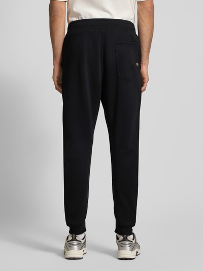 Mężczyzna nosi Sweathose mit Eingrifftaschen od G-Star RAW, czarny kolor, prosty krój, bawełniany miks, tylna kieszeń, widok całej sylwetki z tyłu.