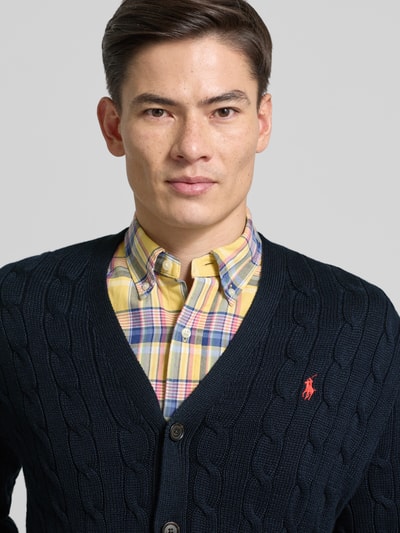 Männermodel trägt Strickjacke mit Knopfleiste von Polo Ralph Lauren aus reiner Baumwolle, Regular-Fit, Label-Stitching, Nahaufnahme Oberkörper.