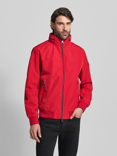 Männermodel trägt Regular Fit Jacke mit Kapuze Modell 'Como' von NAUTGÅRD in Rot, Stehkragen, Zweiwegereißverschluss, Eingrifftaschen, Ganzkörperansicht von vorne.