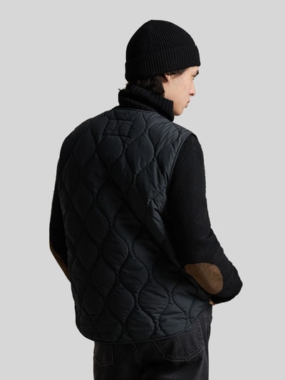 Männermodel trägt Regular Fit Steppweste mit Brusttasche von Polo Ralph Lauren in uni Schwarz mit V-hals en label stitching, ganzkörperansicht rückansicht.