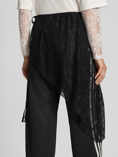 Frauenmodel trägt Loose Fit Sweathose aus Baumwoll-Mix Modell '2IN1 LACE FIREBIRD' von adidas Originals in Schwarz mit asymmetrischer Spitzenlage, Damen Sweathose, Ganzkörperansicht Rückansicht.