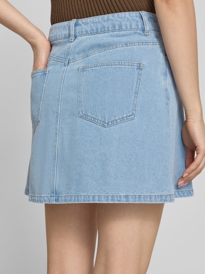 Vrouwenmodel draagt A-lijn jeansrok uit katoenmix met viscose-aandeel model 'ABBI' van Pieces, denim look, mini, 5-pocket, detailopname, achterkant.
