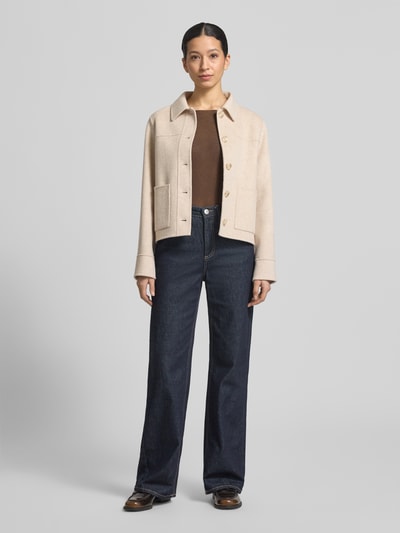 Modelka nosi Jacke aus Lanawolle mit aufgesetzten Taschen od Milano Italy, beżowa, krój regular fit, naszywane kieszenie, widok całej sylwetki z przodu. Długość tyłu w rozmiarze 36: 56 cm, szerokość ramion w rozmiarze 36: 41 cm, szerokość w rozmiarze 36: 53 cm, długość rękawa w rozmiarze 36: 62 cm.