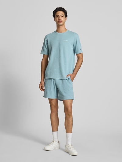 Männermodel trägt Shorts mit Strukturmuster und elastischem Bund von CHAMPION in Hellblau, Baumwoll-Mix, Regular Fit, Ganzkörperansicht von vorne.