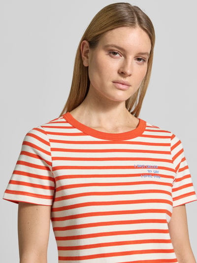 Frauenmodel trägt T-Shirt mit Rundhalsausschnitt und Stitching von Smith and Soul in Orange-Weiß gestreift, reine Baumwolle, Nahaufnahme Oberkörper.