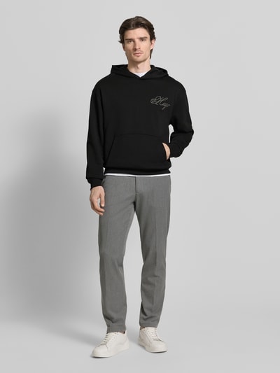 Männermodel trägt Regular Fit Hoodie aus reiner Baumwolle Modell 'DALENTO' von HUGO, unifarben schwarz, Kängurutasche, Ganzkörperansicht von vorne.
