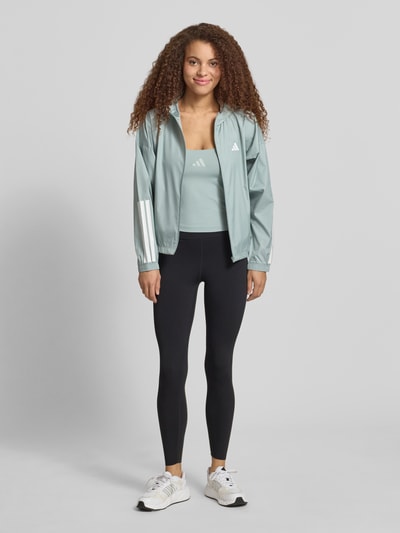 Frauenmodel trägt Slim Fit Sport Top mit Label Print von adidas Sportswear, Optik: Unifarben, Passform: Slim-Fit, Karree-Ausschnitt, Trägerform: Verstellbarer-Spaghettiträger, Materialverarbeitung: Stretch-Webstruktur, Ganzkörperansicht von vorne.