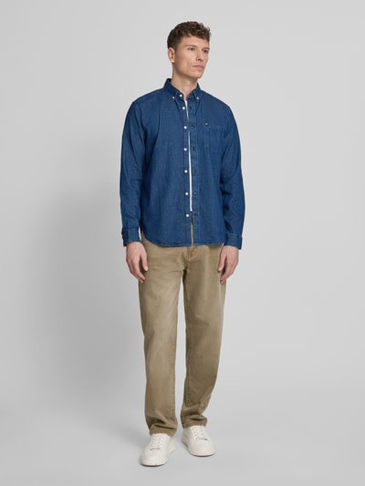 Männermodel trägt Regular Fit Jeanshemd mit Button-Down-Kragen von GAP in Blau aus Baumwoll-Mix mit Stretch-Anteil, Ganzkörperansicht von vorne.