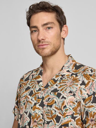 Männermodel trägt Regular Fit Freizeithemd aus Viskose von Scotch & Soda mit Allover-Look, Reverskragen, Brusttasche, Nahaufnahme Oberkörper. Rückenlänge bei Größe M: 74 cm, Schulterbreite: 45 cm, Ärmellänge: 25 cm, bunte florale Muster.