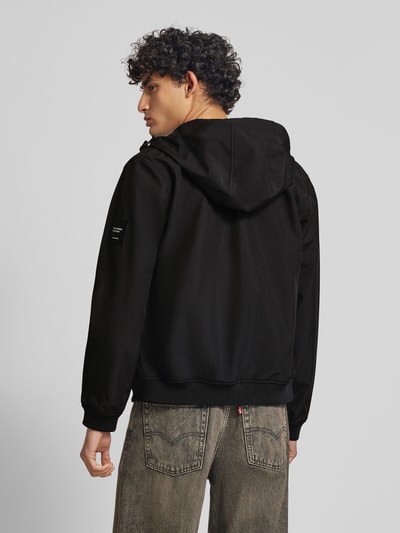 Männermodel trägt zwarte softshell-jack met ritssluiting, ritszakken, capuchon met tunnelkoord van Jack & Jones, regular fit, ruglengte 59 cm, schouderbreedte 39 cm, borstwijdte 48 cm, mouwlengte 62 cm, rugaanzicht