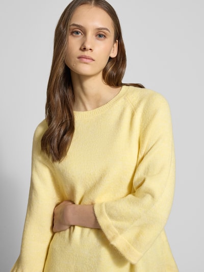 Frauenmodel trägt Oversized Strickpullover mit 3/4-Arm Modell 'SIMONI' von Only in unifarbener gelber Melange-Strickoptik, Nahaufnahme Oberkörper.