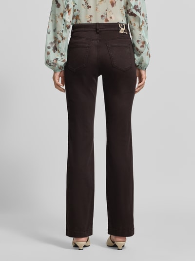 Frauenmodel trägt Flared Fit Jeans mit Lyocell-Anteil von Marc Cain in Dunkelbraun mit 5-Pocket-Design, elastischem Material-Mix, Ganzkörperansicht Rückansicht.