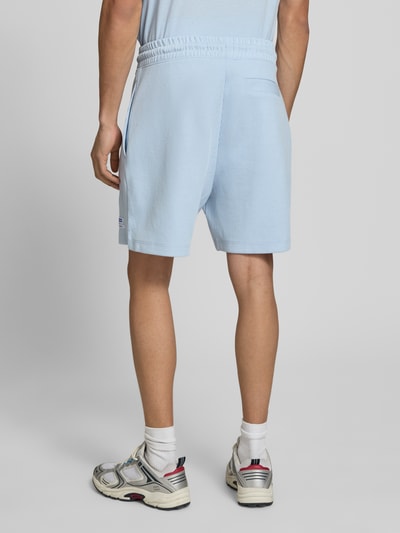 Męski model nosi Regular Fit Sweatshorts aus Baumwoll-Mix Modell 'NUWAFFLO' od HUGO Blue, krój regular fit, jasnoniebieski, gładki, elastyczny pas, łatka z logo, boczne kieszenie, bawełniany miks, widok całej sylwetki z tyłu.