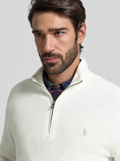 Männermodel trägt Strickpullover mit Label-Stitching von Polo Ralph Lauren in Weiß, aus reiner Baumwolle, Regular-Fit, Nahaufnahme Oberkörper.