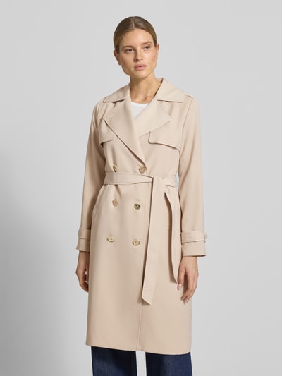Vrouwenmodel draagt Zweireihiger Trenchcoat mit Bindegürtel van MICHAEL Michael Kors in beige met reverskraag, regular fit, met dubbele rij knopen en strikceintuur, ruglengte maat S 47 cm, schouderbreedte 40 cm, borstwijdte 50 cm, mouwlengte 63 cm, geheelopname vooraanzicht.