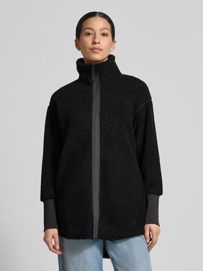 Frauenmodel trägt schwarze Fleecejacke mit Stehkragen Modell 'TOLA' von Didriksons, Relaxed-Fit, Reißverschluss, Ganzkörperansicht von vorne, Kontext: Rückenlänge bei Größe 36 83 cm, Schulterbreite 52 cm, Brustweite 47 cm, Ärmellänge 56 cm.