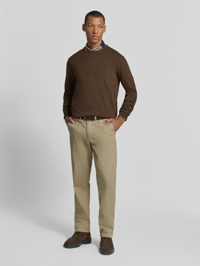 Męski model nosi Strickpullover aus reiner Baumwolle mit Logo-Stickerei od Fynch-Hatton w odcieniu brązu, krój regular fit, z okrągłym dekoltem i prążkowanymi wykończeniami; całkowity widok z przodu.