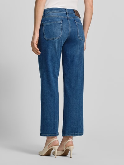 Männermodel trägt Jeans in verkürzter Passform Modell 'TESS' von Cambio, bawełna z elastanem, krój prosty, kieszenie, guziki, szerokość w rozmiarze 36: 40 cm, długość nogawki 71 cm, widok całej sylwetki od tyłu.