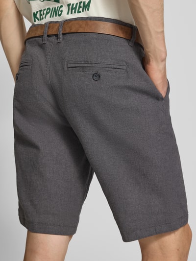 Männermodel trägt Bermudas mit Gürtel und Eingrifftaschen Modell 'NEBRASKA' von Redefined Rebel aus Baumwoll-Mix mit Stretch-Anteil, Ganzkörperansicht Rückansicht.