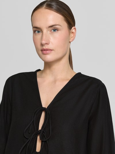 Frauenmodel trägt Blusenshirt aus Viskose-Mix mit Schnürung von Vila, schwarz, mit V-Ausschnitt, Regular-Fit, Nahaufnahme Oberkörper. Kontext: Damen Blusenshirt, Viskose-Mix mit Leinen-Anteil, Modell 'PRISILLA', Rückenlänge bei Größe 36: 56 cm, Ärmellänge: 61 cm.