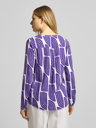 Frauenmodel trägt Wellen-Print Schlupfbluse aus Viskose von Christian Berg Woman in Lila-Weiß, Regular-Fit, Rückenlänge 66 cm, Ganzkörperansicht Rückansicht.